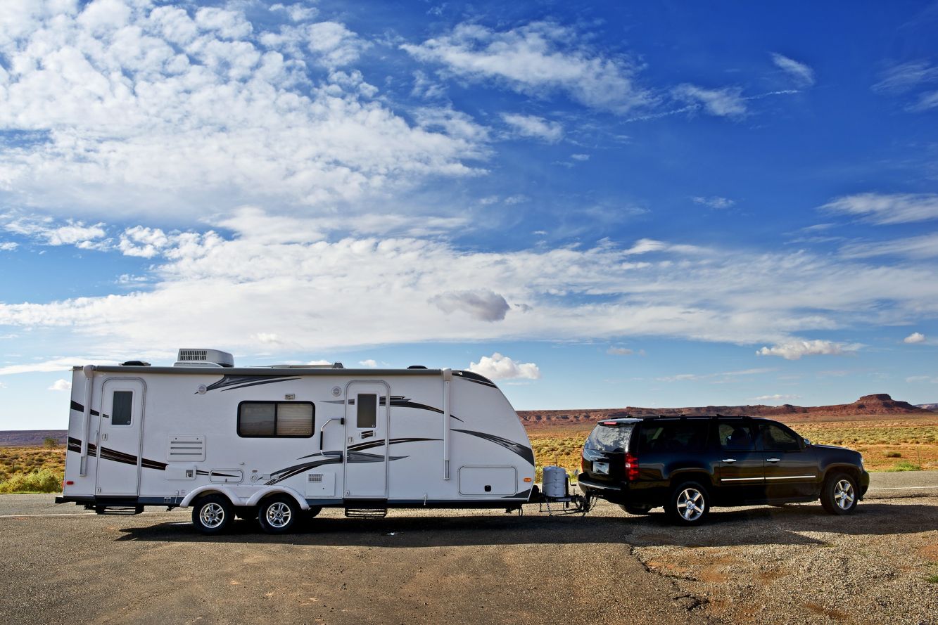 SUV parked hooked up to RV travel trailer in the desert